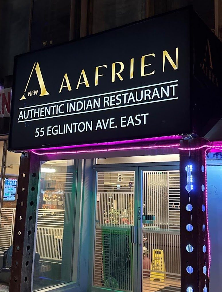 The illuminated Aafrien Indian Restaurant sign on Eglinton Avenue East at night, Toronto