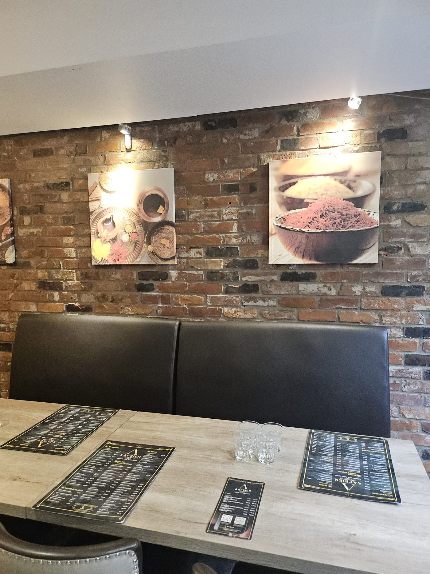 Exposed-brick dining nook with framed art at Aafrien Indian Restaurant, Toronto